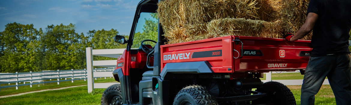 A man loading bales of hay onto a 2019 Gravely UTV